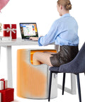 Woman using Under Desk Heater For Home Or Office Quiet Portable Space Warmer To Keep Feet And Legs Toasty as she works at a desk.