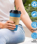 Person holding 100 Pack 16 Oz Disposable To Go Coffee Cups With Lids, Sleeves And Stir Sticks For Grab And Go Hot Or Cold Drinks, Leakproof And Spill Resistant Paper Cups For Office Home Shop Events Navy, with eco-friendly icons.