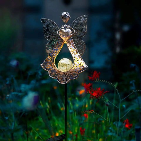 Solar Stake Lights For Garden In Metal Angel Bronze Finish, Warm White LEDs illuminating garden flowers at night.