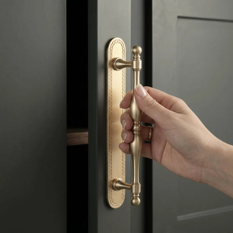 Close-up of hand using Champagne Bronze Cabinet Pulls With Backplates, 2 Pack, 5 Inch Center to Center, on dark cabinet.