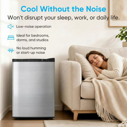 Compact 3.0 Cubic Foot Upright Freezer With Seven Adjustable Temperature Controls And A Sleek Silver Design next to a cozy couch and a sleeping woman.
