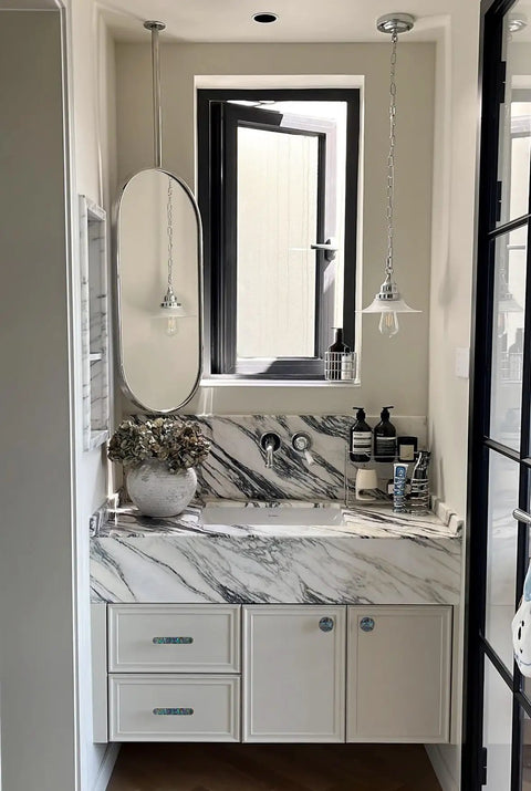 Pearl Shell Cabinet Knobs With Abalone Inlay on white vanity with marble countertop, featuring brushed gold pulls and accessories.