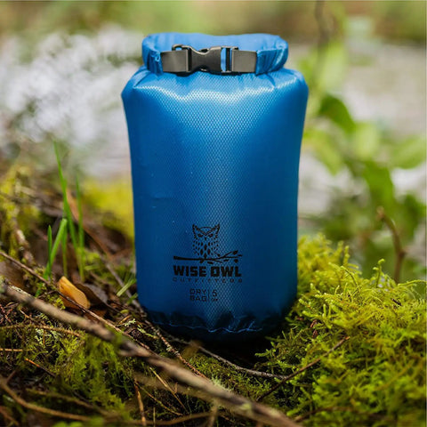 Three Pack Waterproof Dry Bags Set 5L 10L 20L Lightweight Airtight Floating Gear Organizer For Kayaking Beach Travel Boating And Hiking Blue Ripstop Nylon Adventure Ready showing blue dry bag in forest.