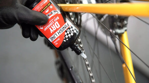 All In One Drivetrain Care Kit With Grunge Brush Dry Lube And EcoTech Degreaser For Cyclists Who Want Quick Clean Smoother Shifts Pro Grade Chain Lubrication And Peak Gear Performance On Every Ride, bottle applying lube to bike chain