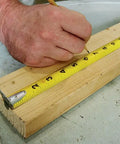 Monster Maggrip 25 Foot Measuring Tape used on wood, yellow with magnetic end, double-sided markings visible in rugged case