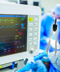 ECG Calipers With Ruler Black Measuring Tool For Nurses And Docs next to an EKG monitor in a medical setting.