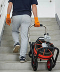 Person carrying a Heavy Duty Auto Feed Drain Auger With 100 Foot Cable And Air Activated Foot Switch on stairs.