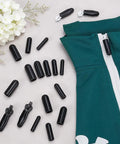 Image shows a 25 Piece Silicone Zipper Protector Covers Guards Set For Laundry Care Includes Five Universal Sizes In Black next to a green fabric with a zipper.