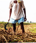 Person using Long Handle Manganese Steel Scythe for gardening in a field, ergonomic grip, one hand use.