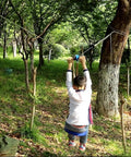 Child playing on Backyard Zip Line Kit 75 Ft For Kids And Adults, Ultra Safe Swing Seat With 60 Mm Thick Cushion, in forest setting