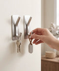 Insane Grip No Drill Towel Hooks Six Pack Silver Rust Proof Heavy Duty Bathroom Wall Mount With Ultra Thick Adhesive holding keys on a wall.