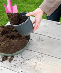 Mini Colorful Metal Hand Shovels Set 10 Pack Garden Trowels For Kids Teens And Adults Perfect For Flower Soil Planting Digging And Transplanting 11 By 3 Inches Durable Metal Garden Tools being used to fill a plant pot with soil.