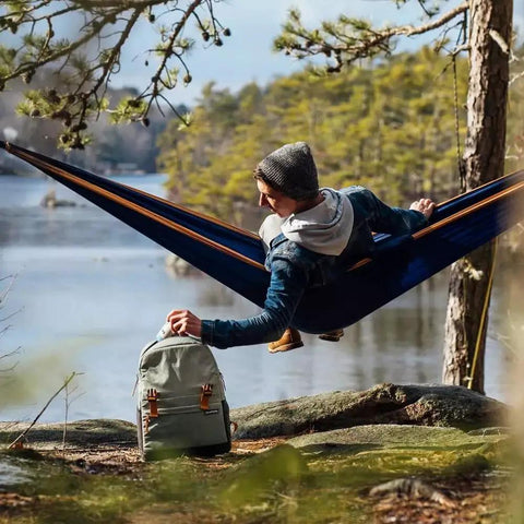 Person in hammock next to Backpack Cooler For 18 Cans With Bottle Opener Leakproof Insulated Cooler Bag For Lunch At Work Beach Camping And Picnics