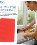 100 Pcs Plastic Door Frame Shims For Windows And Doors next to man measuring window for installation, red composite material visible