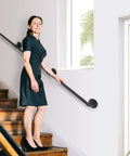 Woman using 10Ft Matte Black Stair Handrails For Indoor Stairs With Wall Mount Support Made From Iron Pipe Railing Durable Rust Resistant
