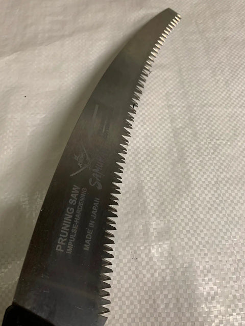 Close-up of Samurai Ichigeki 13 Inch Pruning Saw with Japanese blade, showing sharp TRI CUT teeth and part of the handle.