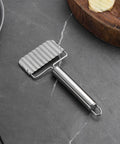 Stainless steel ripple potato slicer with ribbed crinkle blade and long cylindrical handle.