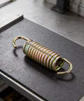 Beefed Up Heavy Duty Lawn Mower Transmission Spring 034-9080-00 on workbench for reliable power transfer