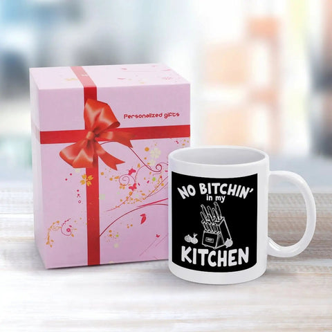 No Bitchin' In My Kitchen 11 Oz Ceramic White Mug With Comfortable Handle Versatile Coffee Cup next to a pink gift box.