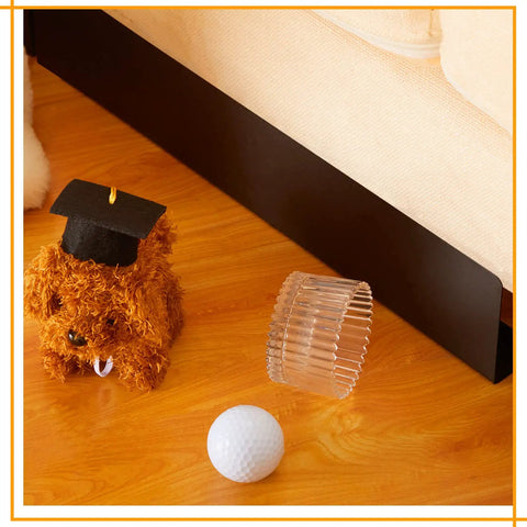 12 Pack Under Couch Blocker Black Pet Barrier Strip To Lock Down Your Sofa Gap and Keep Dogs From Crawling Beneath Furniture With Strong Peel Adhesive Backing And Reusable Guard near a toy dog, clear object, and golf ball.