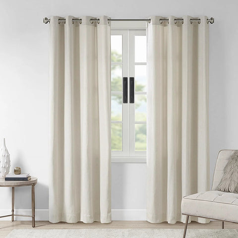 Neutral colored curtains hanging on a window in a cozy living room with a side table and chair.