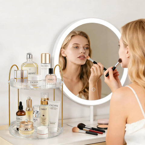 Woman using makeup before mirror with 360 Degree Rotating Makeup Organizer Two Tier No Brainer Large Capacity Tray for skincare and perfume.