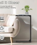 Set Of 2 C Shaped End Tables That Slide Under The Sofa For Easy Laptop Work Or Snack And Drink Tray And TV Tray Space Saving Black Living Room And Bedroom Couch Side Tables with one table beside a sofa with a plant and book on top.