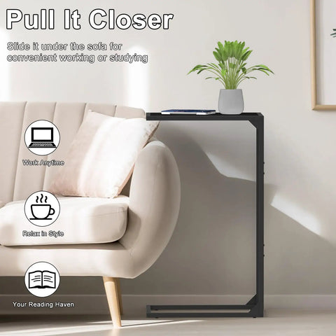 Set Of 2 C Shaped End Tables That Slide Under The Sofa For Easy Laptop Work Or Snack And Drink Tray And TV Tray Space Saving Black Living Room And Bedroom Couch Side Tables with one table beside a sofa with a plant and book on top.