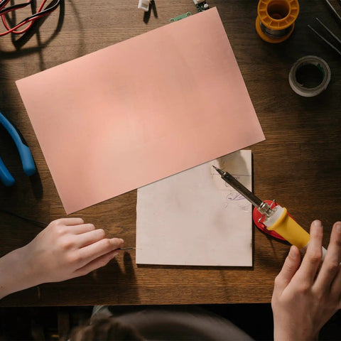 Single Sided Copper Clad PCB Laminate 1.4mm Thick Copper Plated Universal Circuit Board For Etching And DIY Prototyping Kit 20x30cm And 11.8x7.8 Inches For Easy Soldering And Circuit Projects on a workbench with tools