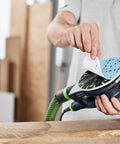 Person attaching Granat 100 Grit 6 Inch Sanding Disc to orbital sander for repairing paints, fillers, and coatings with smooth finish.