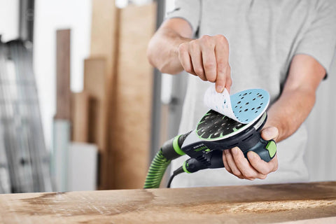 Person attaching Granat 100 Grit 6 Inch Sanding Disc to orbital sander for repairing paints, fillers, and coatings with smooth finish.