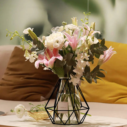 Decorative flowers in geometric black metal cage lampshade vase, displayed on a soft beige cushion background