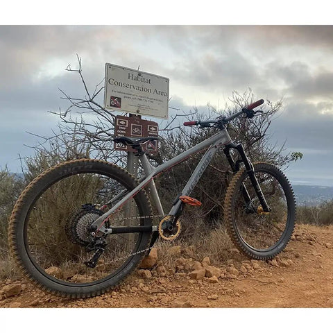 Mountain bike with Ten Speed MTB Groupset Kit With Eleven To Fifty Teeth Cassette standing on rocky trail near a sign