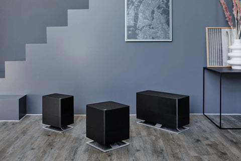 Three black OSKAR Evaporative Humidifiers on a wooden floor in a modern gray room setting