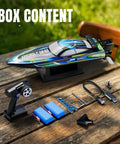 High Speed Brushless RC Boat For Adults With Dual Rechargeable Batteries 30 Minutes Run Time Proportional Throttle And Steering For Lakes 30 MPH Remote Control Boat Ready To Rip Through Waves box content including remote, batteries, charger, and accessories on a table outdoors