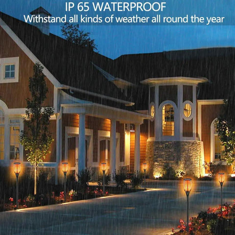 Solar Flame Torch Lights 43 Inch Outdoor Dancing Flames 96 LED Solar Powered illuminating a garden pathway in rain.