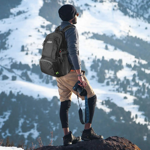 Hiker wearing 40L Lightweight Packable Hiking Backpack With Wet Pocket Waterproof Daypack For Travel Camping And Outdoor Adventures Durable And Easy To Carry For Rainy Trails in snowy mountains