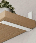 Heavy Duty Floating Shelf Brackets 10 Inch L Shape Metal Wall Mount Supports Smooth Matte White 160 Pound Capacity 6 Pack on wooden shelf.
