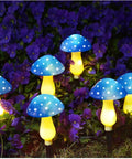 Six Pack Blue Solar Garden Mushroom Stake Lights With Eight Lighting Modes For Outdoor Yard Decor glowing among purple flowers.