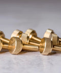 Top Shelf Brass Knurled Thumb Screws Ten Pack One Quarter Twenty Thread Three Quarter Inch Length Diagonal Grip on a surface.
