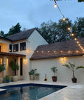 24 Ft Outdoor Hanging String Lights With 12 Vintage S14 LED Bulbs illuminating a cozy backyard patio with pool at dusk.