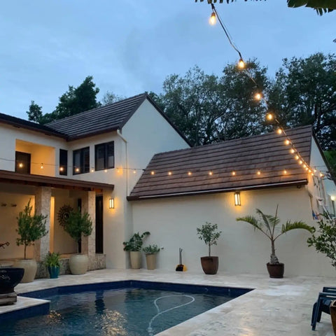 24 Ft Outdoor Hanging String Lights With 12 Vintage S14 LED Bulbs illuminating a cozy backyard patio with pool at dusk.