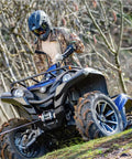 ATV equipped with Hub Wireless Receiver for Powersports Winches with Bluetooth Smartphone Control on a muddy trail.