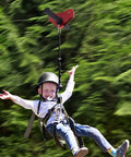 Child enjoying Backyard Zip Line Kit For Kids And Adults Up To 330 Lb, 120 Ft Stainless Steel Zip Line With Spring Brake and Helmet