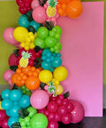 Hawaiian Summer Balloon Arch Kit With 129 Pieces In Hot Pink Teal Blue Lime Green Yellow Orange And Confetti For Totally Dope Tropical Party Vibes And Easy Indoor Outdoor Celebrations decorating a pink backdrop.