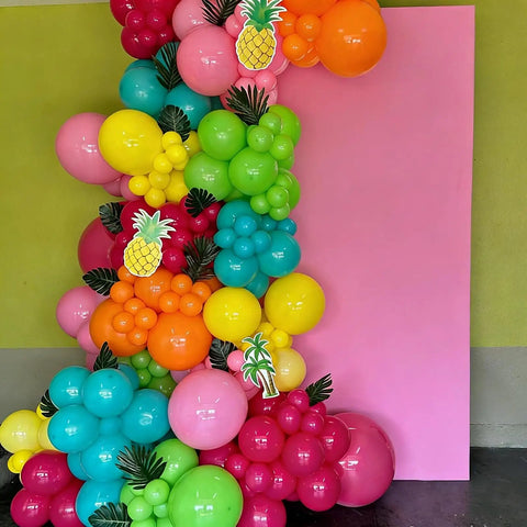 Hawaiian Summer Balloon Arch Kit With 129 Pieces In Hot Pink Teal Blue Lime Green Yellow Orange And Confetti For Totally Dope Tropical Party Vibes And Easy Indoor Outdoor Celebrations decorating a pink backdrop.