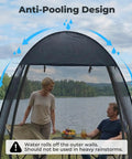 Pop Up Screen Tent 6x6 Feet Black Mesh Gazebo With Peaked Roof shown outdoors by a lake with two people seated inside.