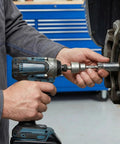 Using Two Piece Backup RV Jack Socket Drill Adapter with cordless drill on a vehicle part in a garage setting.