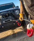 Person holding Flatlink E Expert Winch Hook Alternative With Folding Shackle And D-Ring Mount, Jeep in background