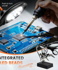 Silver Handheld Magnifier Glass With Stand For Reading Small Print And Detailed Craft Work, focused on circuit board soldering with LED light